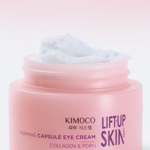 Otwarty słoiczek "Kimoco Lift-Up Skin Firming Capsule Eye Cream" z widocznym białym kremem z drobnymi niebieskimi kapsułkami, na jasnoróżowym tle
