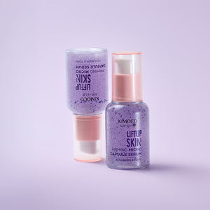 Z prawej stojąca butelka "Kimoco Lift-Up Skin Firming Micro Capsule Serum" z fioletowym serum, z lewej taka sama butelka odwrócona do góry nogami, na jasnoróżowym tle.