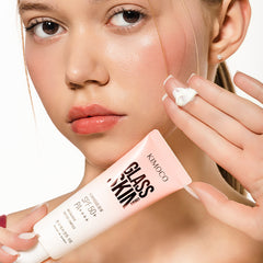 Zdjęcie na białym tle: u góry twarz kobiety z rumieńcem na policzku i dłonią z kremem na palcach uniesioną przy twarzy, u dołu tuba "Kimoco Glass Skin Luminous Dew SPF 50+ PA+++" trzymana w drugiej dłoni.